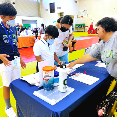 On May 21, Guam Early Hearing Detection & Intervention (EHDI) staff participated in the Guam Head Start Program 2022 Fitness Fair at Dededo Sports Complex. The event provided activities and resources for parents, children, and families to engage in a healthier lifestyle. Tanya Simer, Guam EHDI Hearing Screening Facilitator (pictured right), gave instructions for the “Spell Your Name” workout activity to the family. The activity used the letters of the alphabet to complete exercises for movement. 